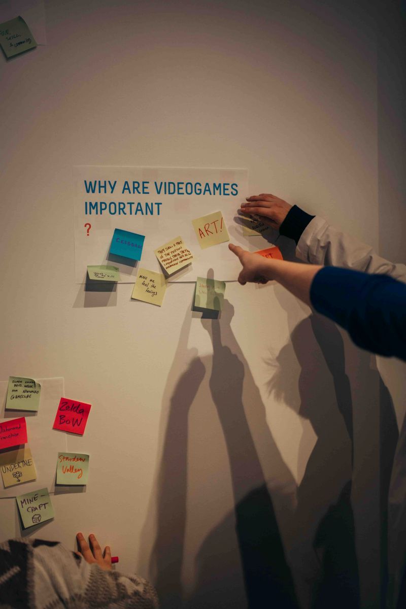 Jam participants point at a sign that says 'Why Are Videogames Important?'