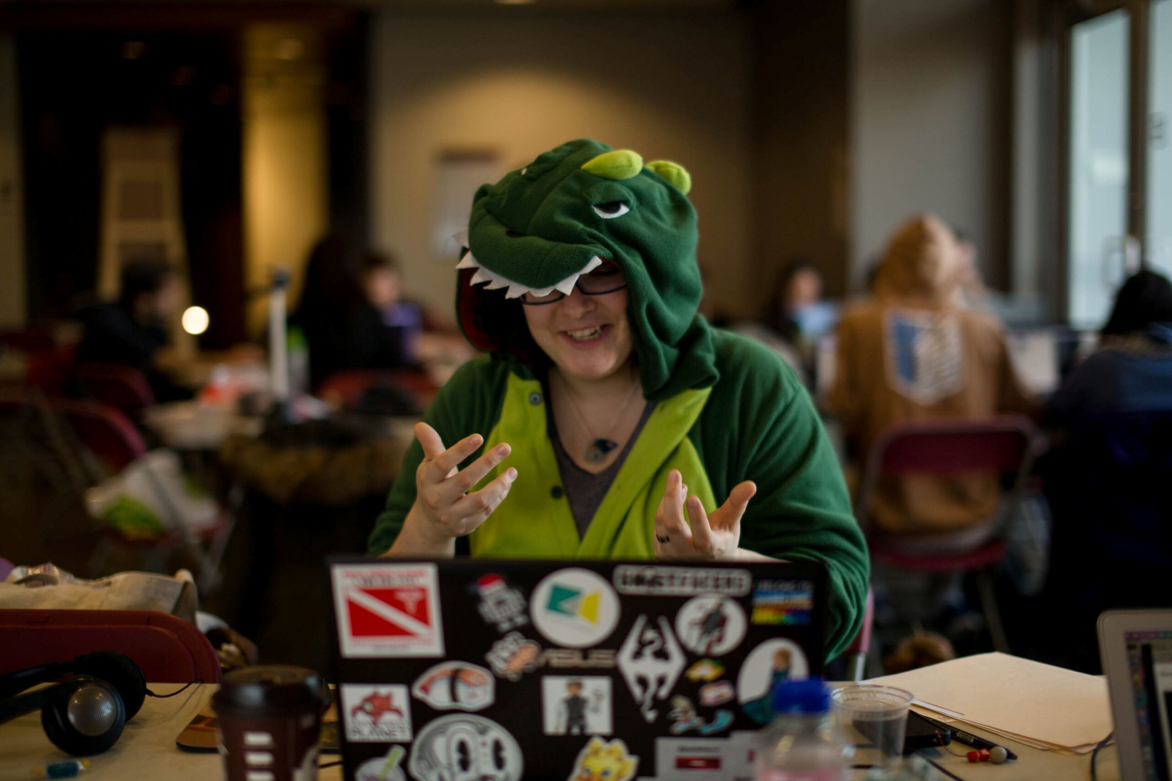 A jam participant in a dinosaur onesie sits in front of their laptop